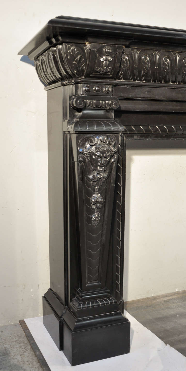 This exceptional and unique antique fireplace was made out of Black from Belgium marble in the 19th century. The work of sculpture puts this fireplace in the realm of statuary creation. The flutted jambs are adorned in thei upper part of Satyrs