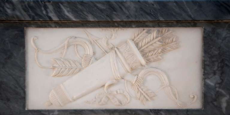 This beautiful antique Directoire period fireplace was realized in the 1820's. Made out of Blue Turquin marble, this fireplace is ornated with carved Statuary Carrara marble cabochons. The center of the frieze is carved in low-relief with a quiver