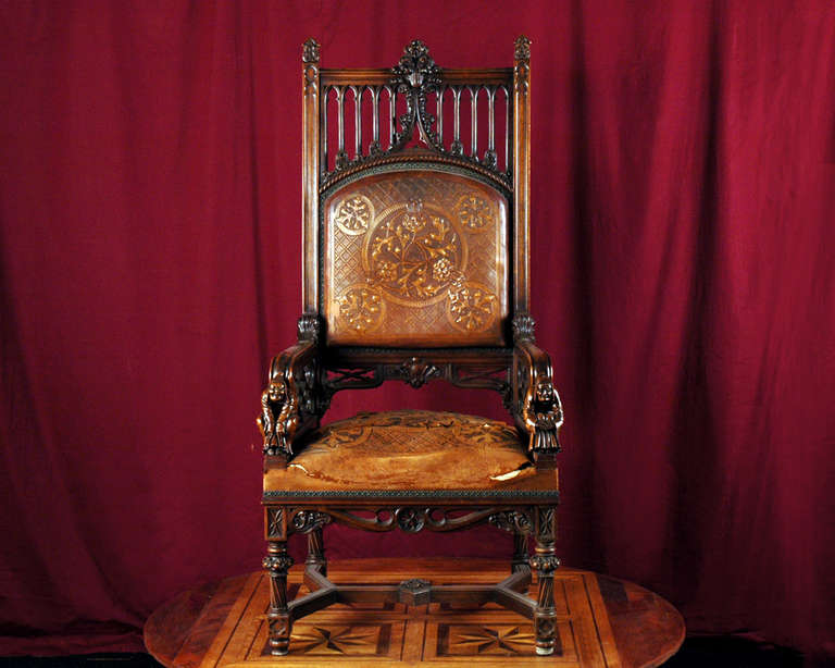 This large armchair was realized in a Neo - Gothic style. It was made out of carved walnut and embossed leather circa 1840-1850. The sculpted ornaments of this armchair are deeply inspired by the Gothic architecture. Thus, the upper part of the