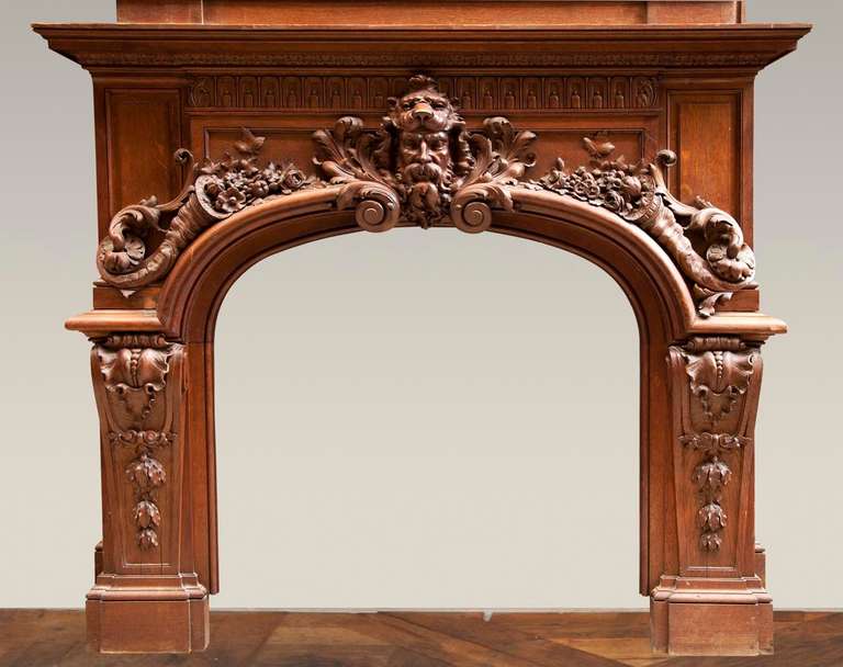 This rare monumental oak wood fireplace was realized after the model of the fireplace which takes place in the Hercules Salon at the Versailles Palace. Regence style, the fireplace carries a somptuous carved decor. In the center of the frieze, we