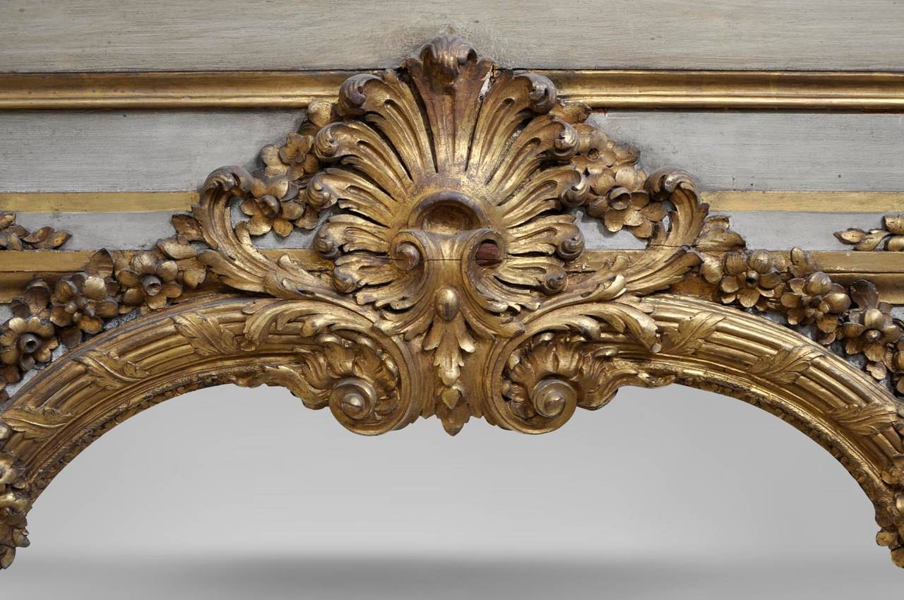 This antique overmantel was made during the 19th century, in Louis XV style, in carved and gilded wood. 
Very detailed decor with shells, foliages and chimeras.