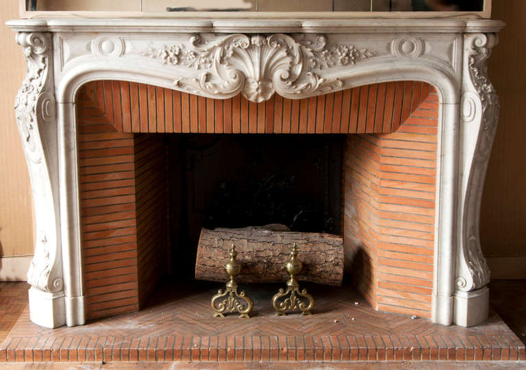 Dieser reiche antike Kamin im Stil Louis XV wurde im 19. Jahrhundert aus weißem Carrara-Marmor gefertigt. Der konturierte Fries ist reich geschnitzt und zeigt eine zentrale Muschel, die von naturalistischen Akanthusblattgirlanden und realistischen
