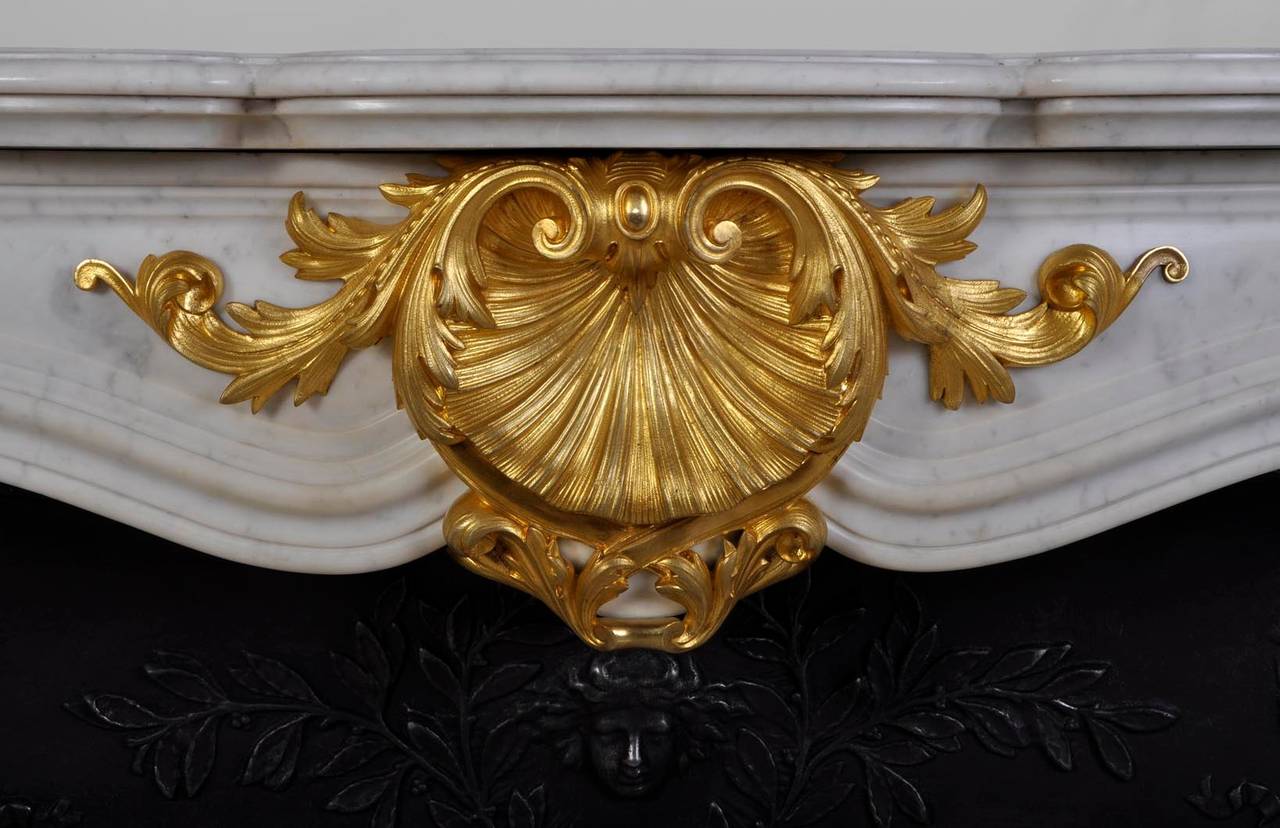 All sculptures are in gilded bronze. Beautiful sculpture and ciseling of the central shell.
This fireplace comes with a modern cast iron insert with woman mask and cornucopias decor. This mantel can be matched with another mantel from the same