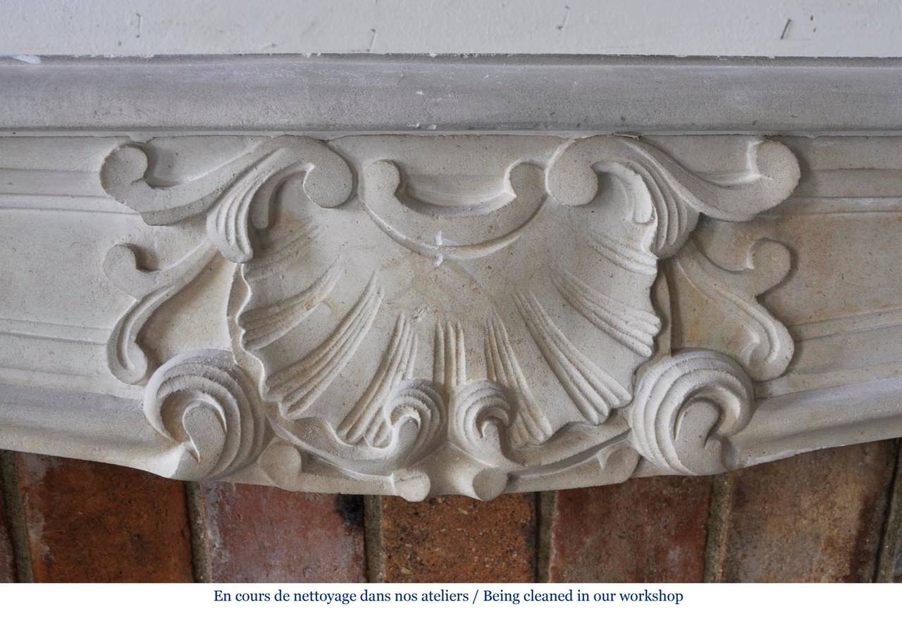This Louis XV style fireplace was carved in stone circa 1900. The frieze is ornated with a large shell. 
The fireplace comes with its original stone floor.