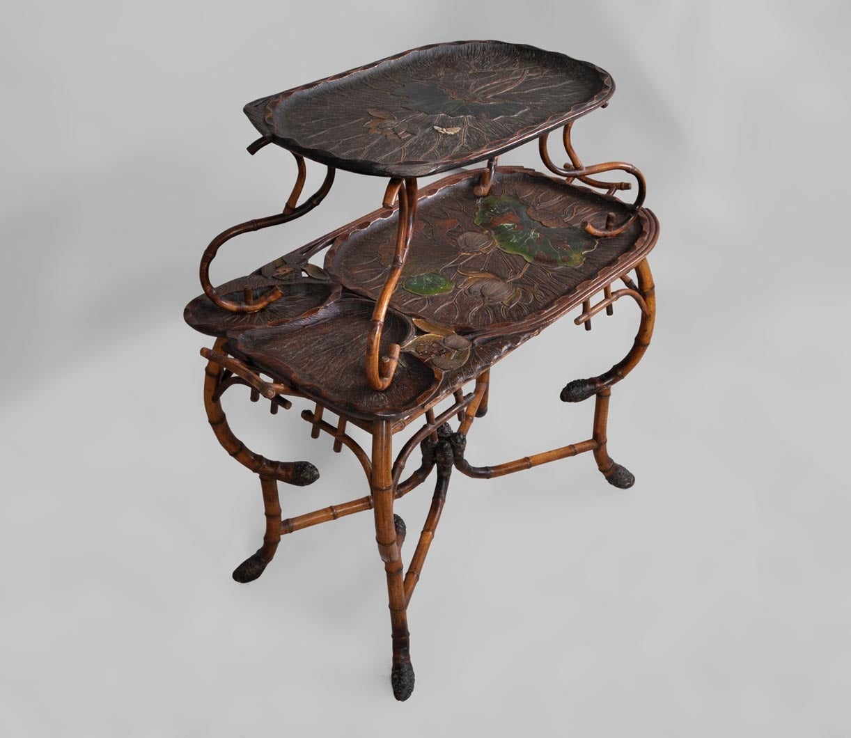 This table bears the mark of the DAÏ NIPPON, a Parisian cabinetmaker from the late 19th century. Daï Nippon was specialised in the Japanese style. 
This tea table is made of bamboo with curved legs. The decor is engraved and lacquered, also with