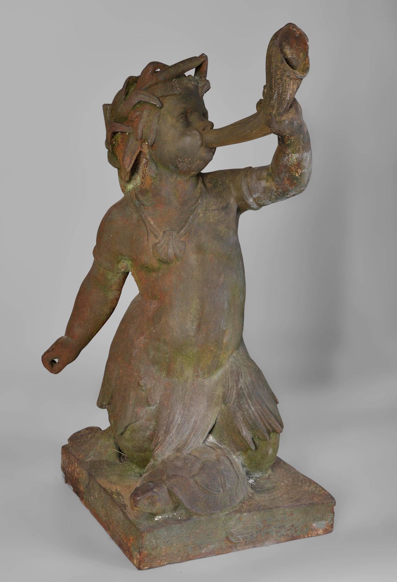 This antique 19th century cast iron statue is the center of a fountain. The Triton is blowing in a horn. 
The base of the statue is signed by the Val d'Osne foundry. 
We can see the same tritons in the monumental fountain in the Saint James Courts