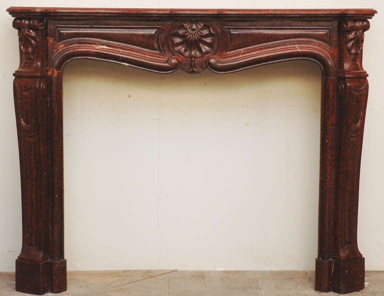 This antique Louis XV style fireplace was realized in the late 19th century in a beautiful Red Griotte marble. The frieze is decrated with a carved reversed shell, as  the head of the legs.