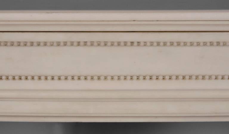 This antique Louis XVI style fireplace is quite a rare model. Curved, the frieze is decorated with pearls. Both sides are paneled and curved. Jambs are fluted and ornated with asparagus heads. 
The fireplace is sold with an antique cast iron insert.