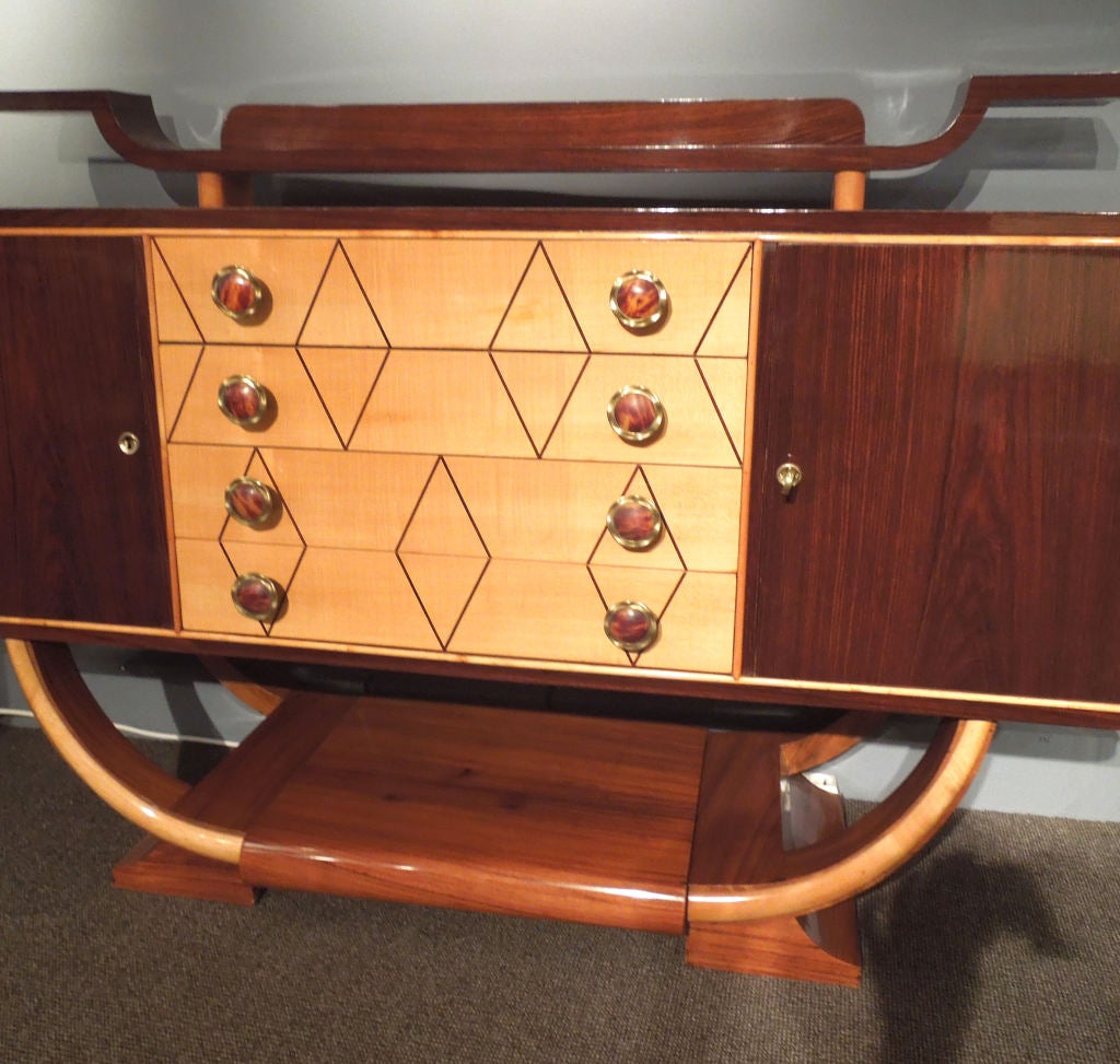 A nice proportion and elegant  sidebord from 1930.Italian art-deco with a little touch of Japonese style. Dark rosewood and beech.Four drawers and two cabinets.Handels are in backelit and brass.
