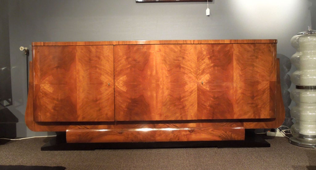 Walnut and blond mahogany veneered art-deco sideboard on black lacquered wooden base.Inside one shelf behind the door on the left hand side and shelves and drawers on the other side.Nice proportions.