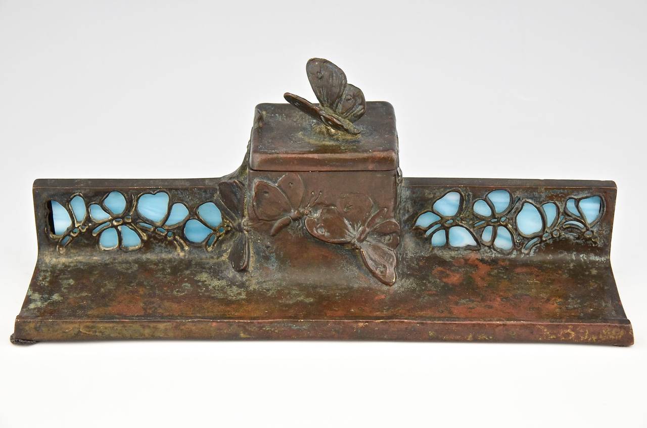 Bronze inkwell with butterflies.
Style:  Art Nouveau. 
Date:  1900. 
Material:  Patinated bronze with glass inlay. 

Size: 
H 3.9 inch. x W 4.1 cm. x L 10.2 inch. 
10 cm. x W 10.5 cm. x L 26 cm.