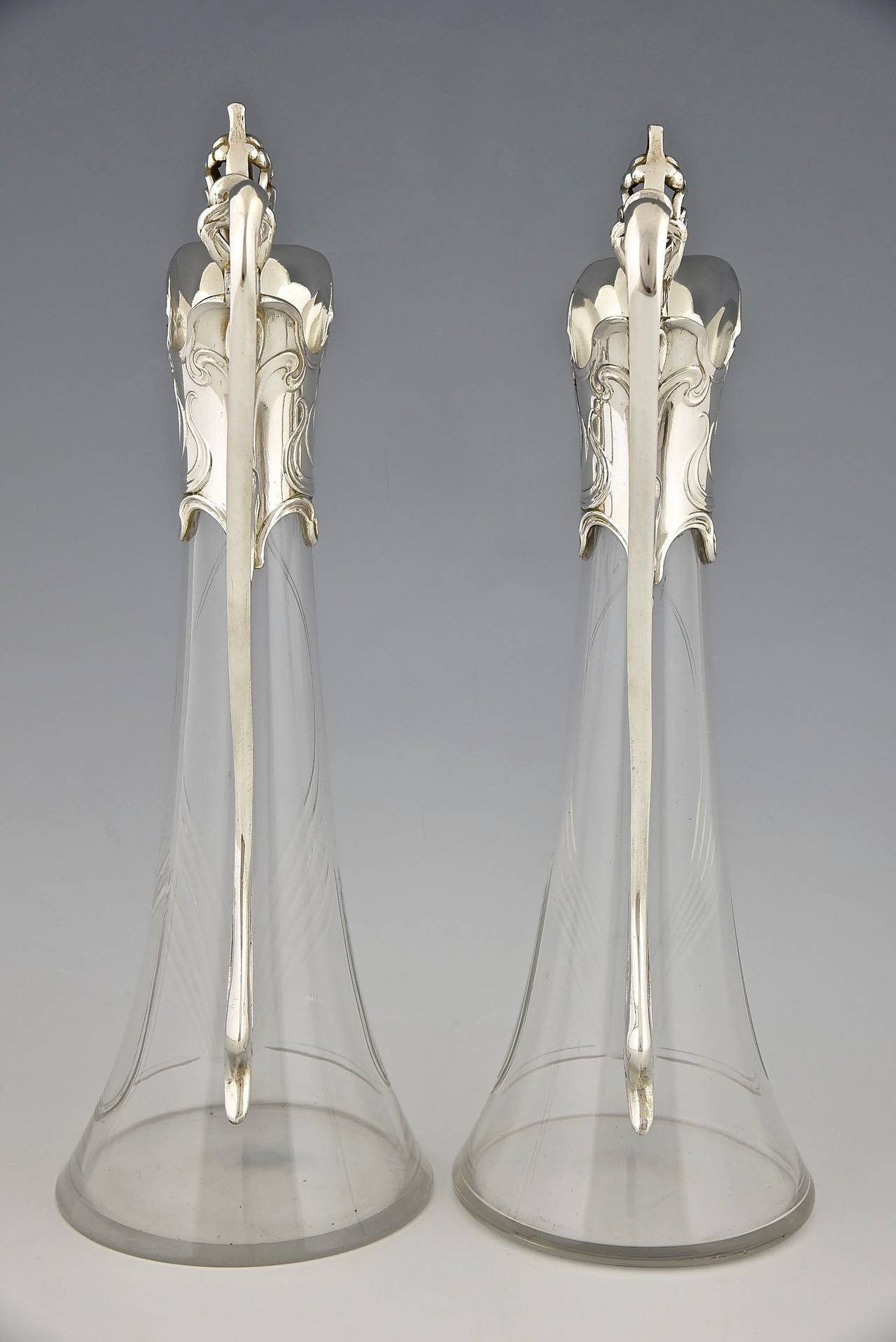 A pair of Art Nouveau claret jugs.
By  WMF, Württembergische Metallwarenfabrik. 
Marks:  WMF mark, B, o/1, as.
Style:  Art Nouveau. 
Date:  1906. 
Material:  Britannia Metal, silver plated.  Original glass. 
Origin:  Germany. 
Size: 
 H 15.4