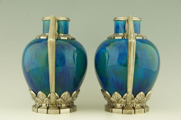A pair of French Art Deco ceramic vases with “blue flambé” glaze and great detailed silvered bronze mounts. 
There are gold specks in the intense colored green/blue glaze. 
By Paul Milet (1870-1950) son of Optat Milet for Sèvres.