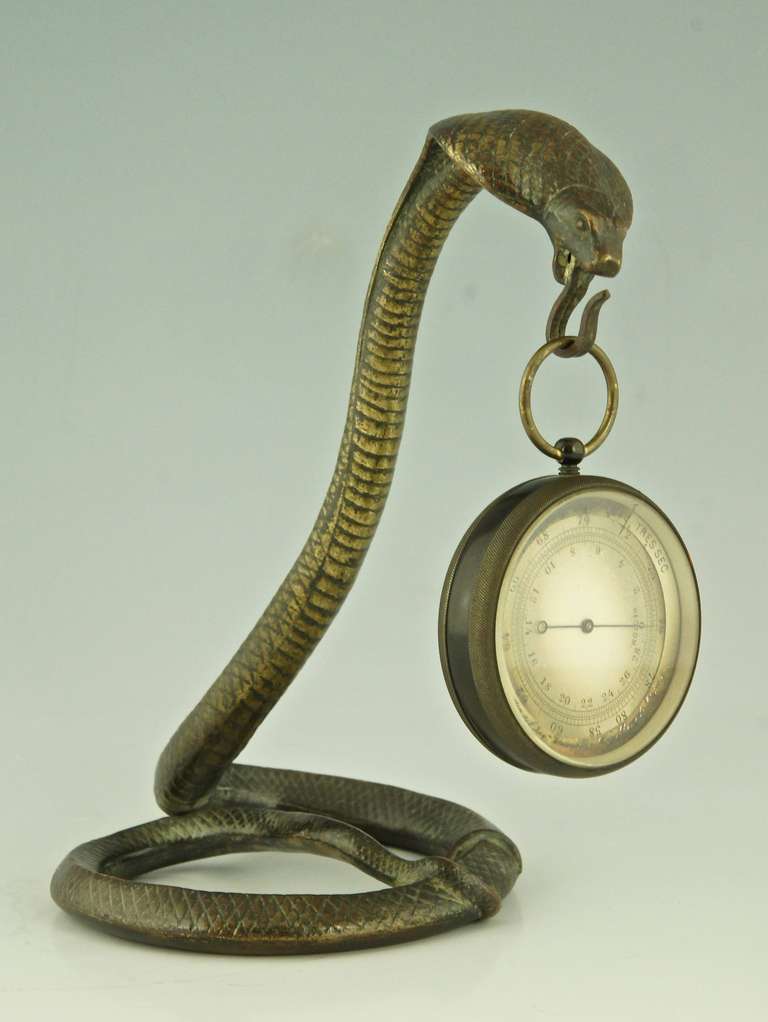 A bronze cobra snake pocket watch stand by  Edgar Brandt. 
Stamped E. Brandt.
Style:  Art deco.
Date:  1920.			
Material: Bronze.
Origin: France.	
Size: 
H. 19,5 cm x L. 18 cm x W. 12,5 cm. 
H. 7.7 inch x L. 7.1 inch x W 4.9 inch. 			