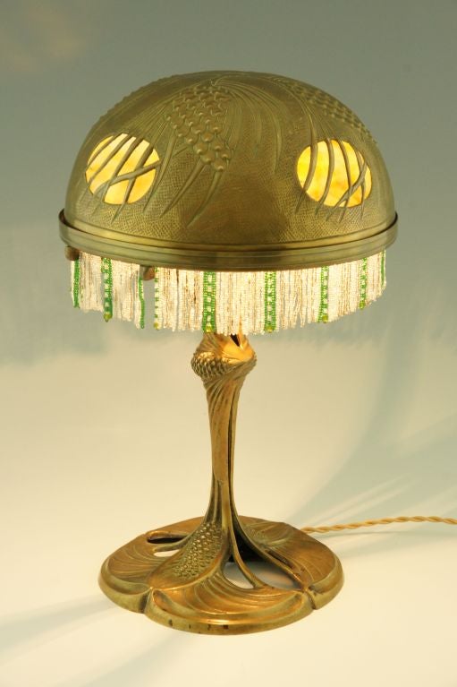 An art nouveau bronze, brass and glass table lamp decorated with pine cones. 

Literature:
A similar model is illustrated on page 127 of
“Lampen und Leuchter, Art Nouveau to Art deco” Wolf Uecker, Schuler.
“1000 lights” by Taschen.
“Le