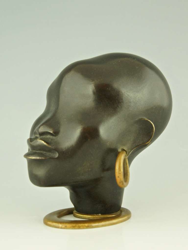 A head of an African women with earring on oval base by F. Hagenauer	 

Signature & Marks:  
WHW	 
Made in Vienna Austria. 
Hagenauer Wien Handmade

Style:  Art Deco.  
Date:  1930.
Material:  Bronze.		 
Origin:  Vienna, Austria.