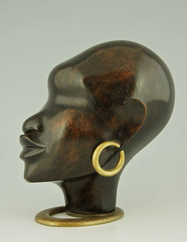 A head of an African women with earring on oval base. 
Artist/ Maker:  Hagenauer F.		 

Signature/ Marks:  
WHW	 
Made in Vienna Austria. 
Hagenauer Wien 
Handmade

Style: Art Deco.  
Date:  1930.
Material:  Wood and bronze..		 
Origin:
