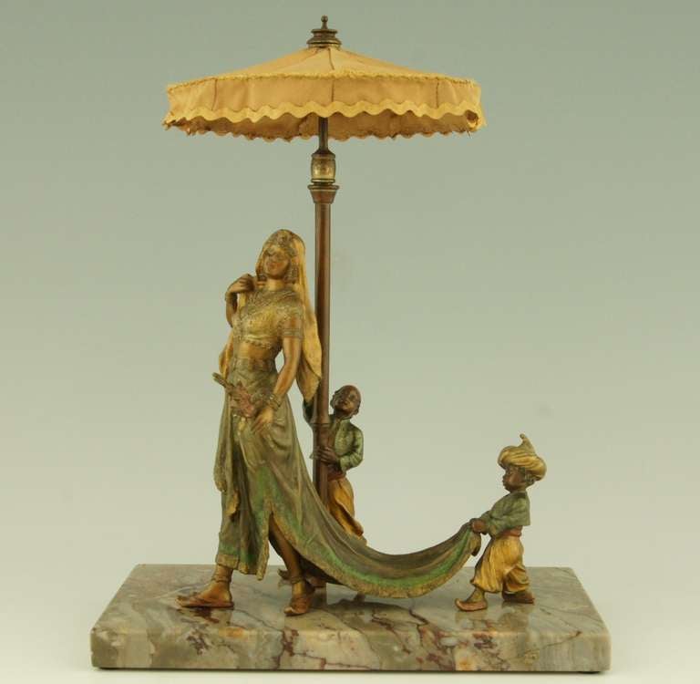A cold painted Vienna bronze of an Arab woman attended by two boys one holding the parasol the other the train of her dress. Mounted on a marble base by Nam Greb or Franz Bergman.

Signature and marks: Nam Greb. B in a double handled vase.