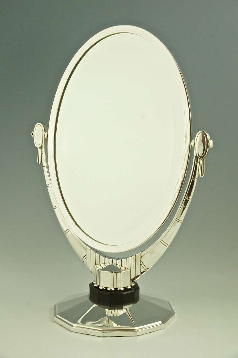 An oval Art Deco mirror with beveled glass by Atelier Raynaud, France. 

Signature/ Marks:  
DR for Raynaud.  
Prat Oran, stamp of the jeweler where the mirror was sold.  
Stamped number.   

Style:  Art Deco.		
Date:  1930.			
Material: 