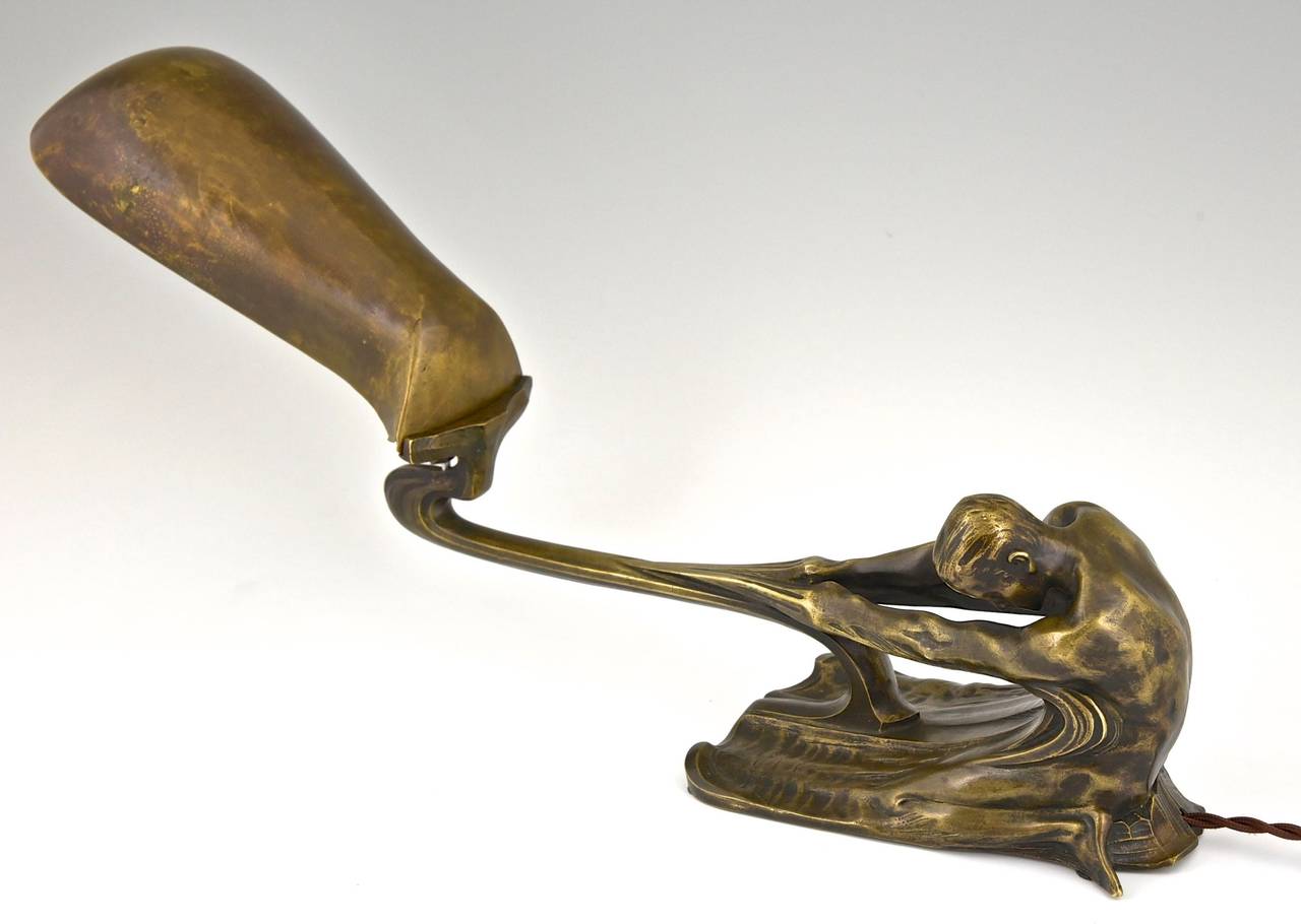 An Art Nouveau bronze piano or desk lamp with a male nude and a hammered brass shade signed by Wetzel. 
Style: Art Nouveau. 
Date: 1900. 
Material: Patinated bronze, hammered brass shade.
Origin:  Europe. 
Dimensions: Size:  
H 9 inch x L 18.5
