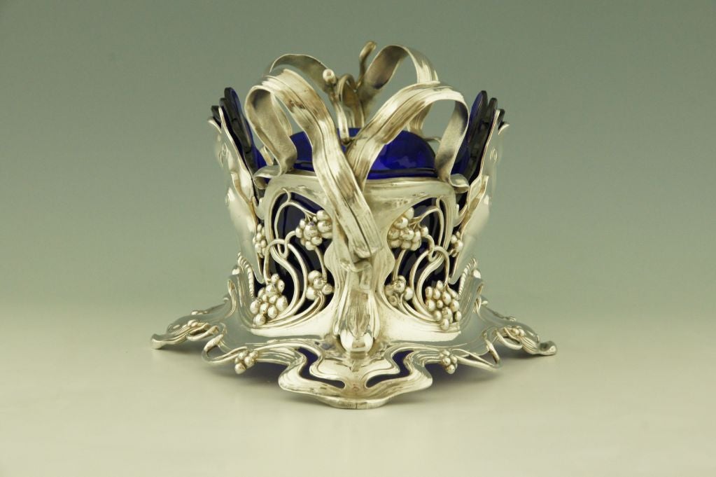 An Art Nouveau flower dish with butterflies and a blue glass liner. 
A picture of this model is shown on page xli of the book
”Art nouveau domestic metalwork from Württembergische Metallwaren Fabrik 1906” published by the antique Collectors Club.