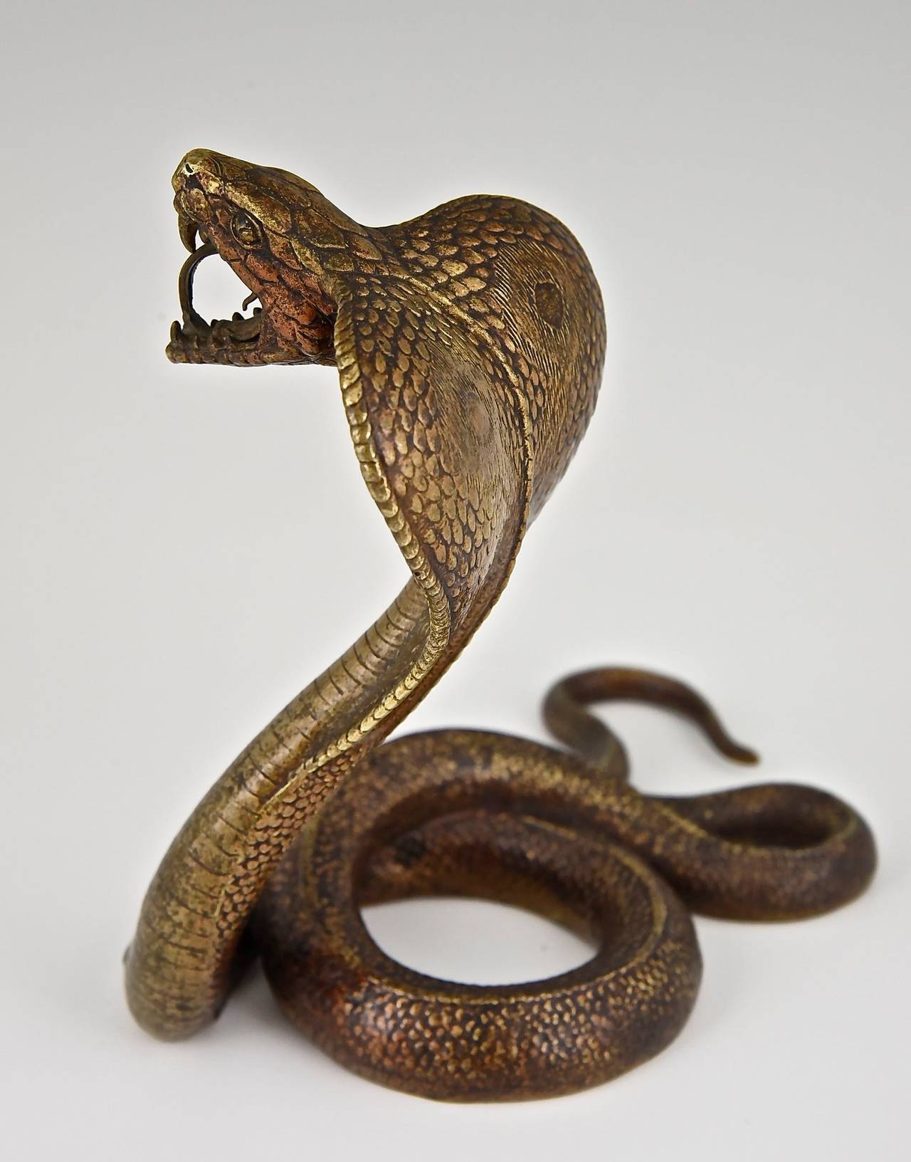 Description:  A Vienna bronze cobra. 
Artist/ Maker:  Nam Greb, Franz Bergman
Signature/ Marks: Nam Greb.  B in a double handled vase. 		
Date:  1900.			
Material:  Patinated bronze.
Origin:  Vienna, Austria. 			
Size:			 
L. 6.7 inch. x W.