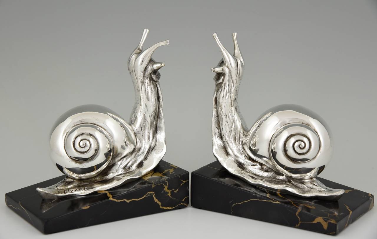 Art Deco bronze snail bookends. 
By Suzanne Bizard. 
Signature:  S. Bizard.
Style:  Art Deco. 
Date:  1930.
Material:  Silvered bronze.  Portor marble bases.
Origin:  France. 
Size of one:  
H. 5.7 inch x L. 4.9 inch x W. 3.3 inch
H. 14.5