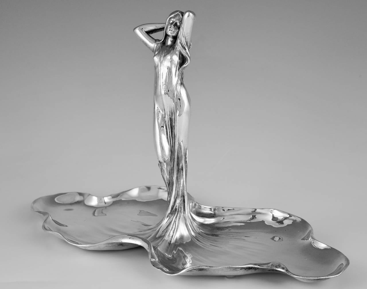 Description:  An Art Nouveau sweet and fruit dish with an art nouveau maiden. 
Artist/ Maker: WMF, Württembergische Metallwaren Fabrik. 
Signature/ Marks:  WMF mark, B, as,1/0
Style:  Art Nouveau. 
Date:  1906. 
Material:  Britannia metal,