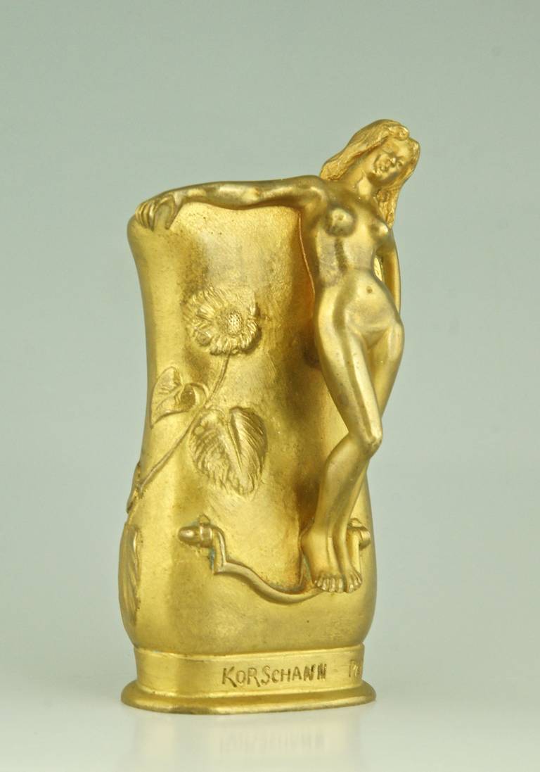 A gilt bronze vase with a nude.  The background is decorated with flowers. 
By  Charles Korschann.
Signature and Marks:  Charles Korschann, Paris.  Foundry stamp Louchet.  
Style:  Art Nouveau. 
Condition:  Good original condition.
Date: circa