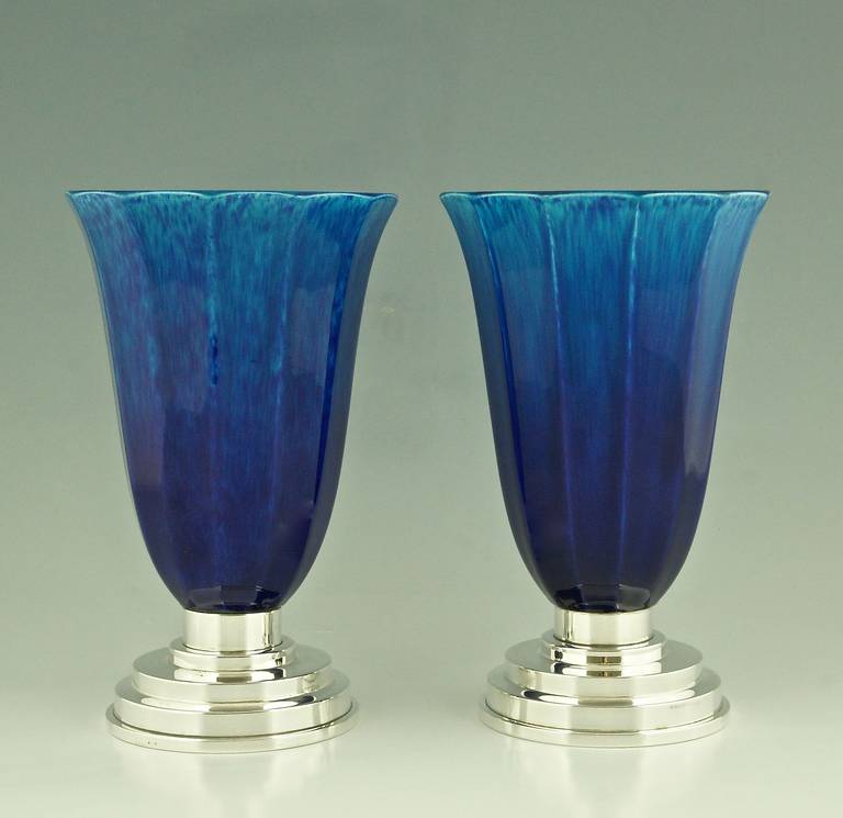 A pair of French Art Deco ceramic vases with blue glaze on silvered bronze bases.
Artist and maker:  Paul Milet (1870-1950) son of Optat Milet. 
Maker:  Sèvres.
Signature and marks:  MP and Sèvres dotted circle logo, bases marked bronze. 
Style:
