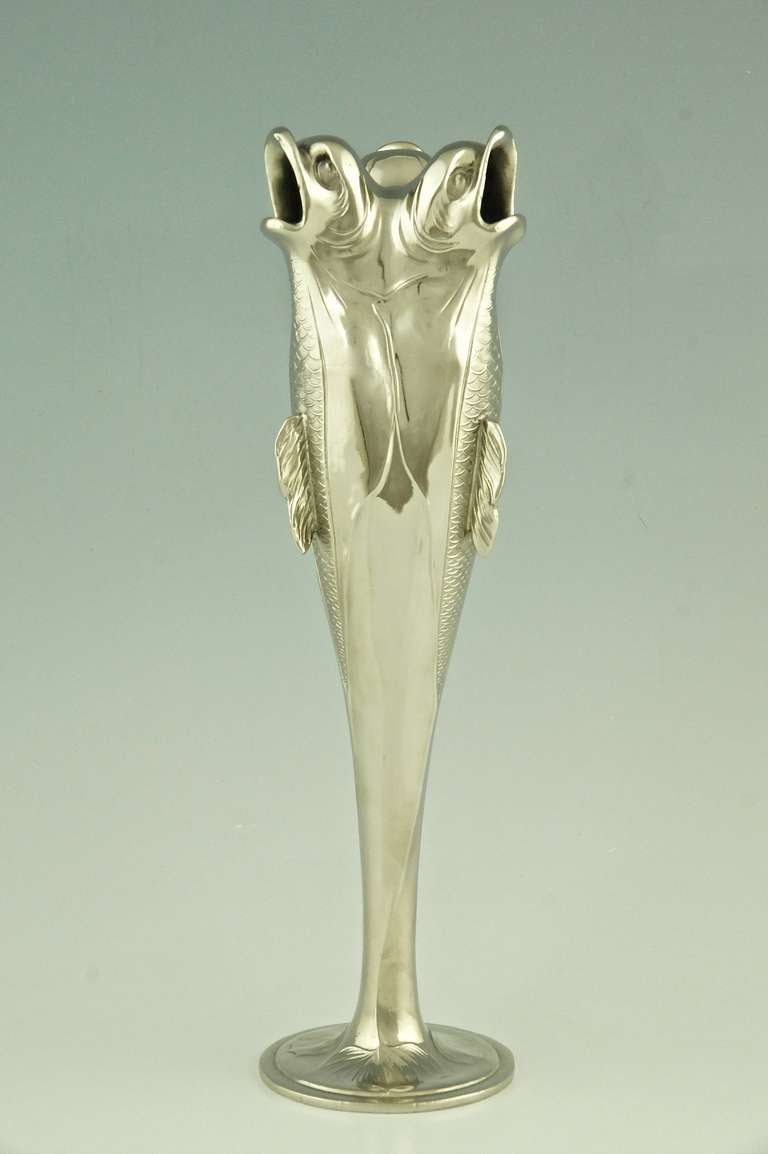 An art nouveau vase shaped like three upright fishes, their tails forming a circular foot.  
By Hermann Gradl for Osiris.
Signature & Marks:  Stamped number 517.  Indistinct mark. 
		
Size:			
 H. 32 cm  x D. 8.7 cm. 
 H. 12.6 inch x D. 3.4
