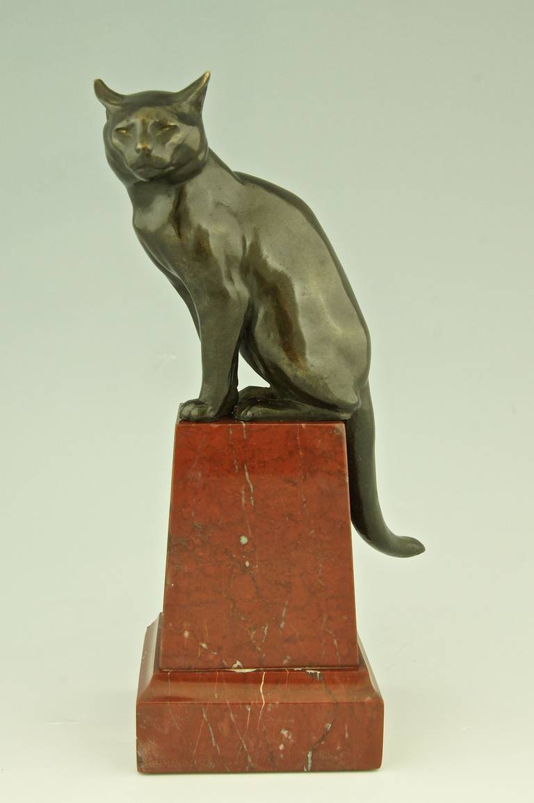 Art Deco bronze sculpture of a sitting cat. 
Style:  Art Deco. 
Date:  1920.
Material:  Patinated bronze.  Red marble base.
Origin:  France.

Size:  
H. 9 inch. x W. 3.5 inch. x L. 4.7 inch.  
H. 23 cm x W. 9 cm x L. 12 cm.