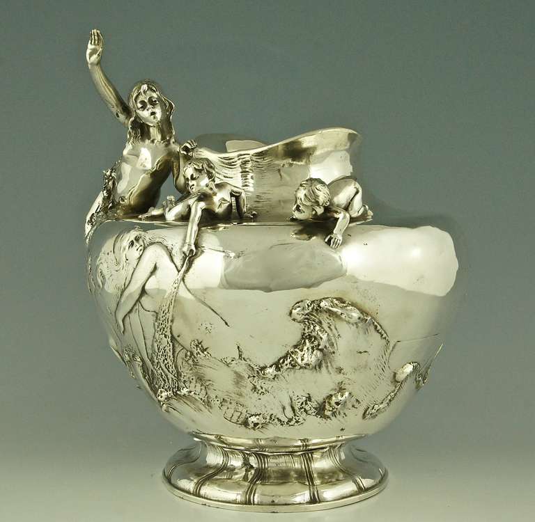 An Art Nouveau flower vase with mermaid and cupids on the rim.  In the water you see 3 nudes and a fish. Birds are flying over the water. 
Artist:  W. Hareng, Paris.

Size:		
H. 13 inch x L. 12.6 x W. 11.4 inch. 	 
H. 33 cm x L. 32 cm x W. 29