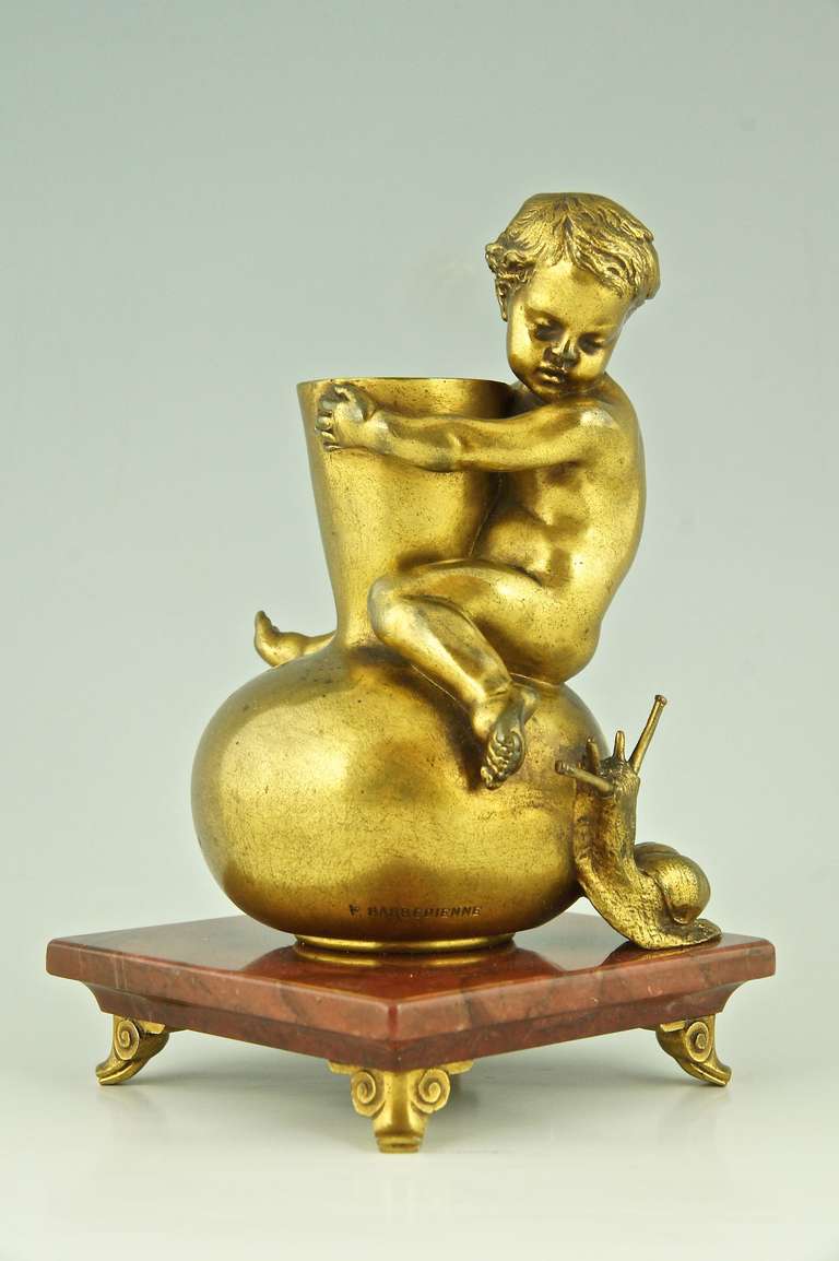 Antique bronze of a little boy sitting on a vase staring at a snail. 
By Louis Ernest Barrias.
Signature / Marks :  E. Barrias, Foundry mark: F. Barbedienne	

Date:  1880.			
Material:  Gilt bronze, red marble base.
Origin:  France.