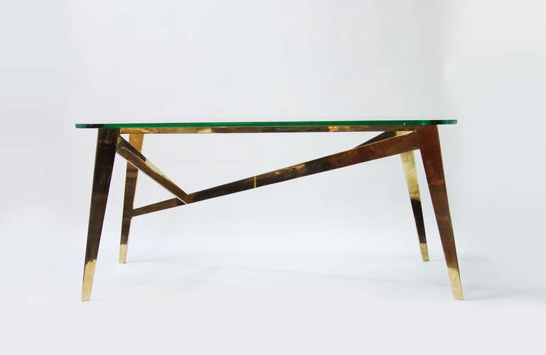 Table composed of a Fontana Arte glass table top resting on a welded brass structure.
