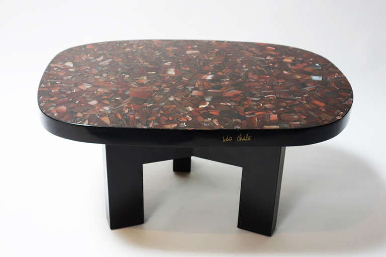 Coffee table composed of a resin tabletop with cornelian agate inlays, resting on a tripod metal foot.

Ado Chale signature brass plate an ruby inlaid into the tabletop edge.