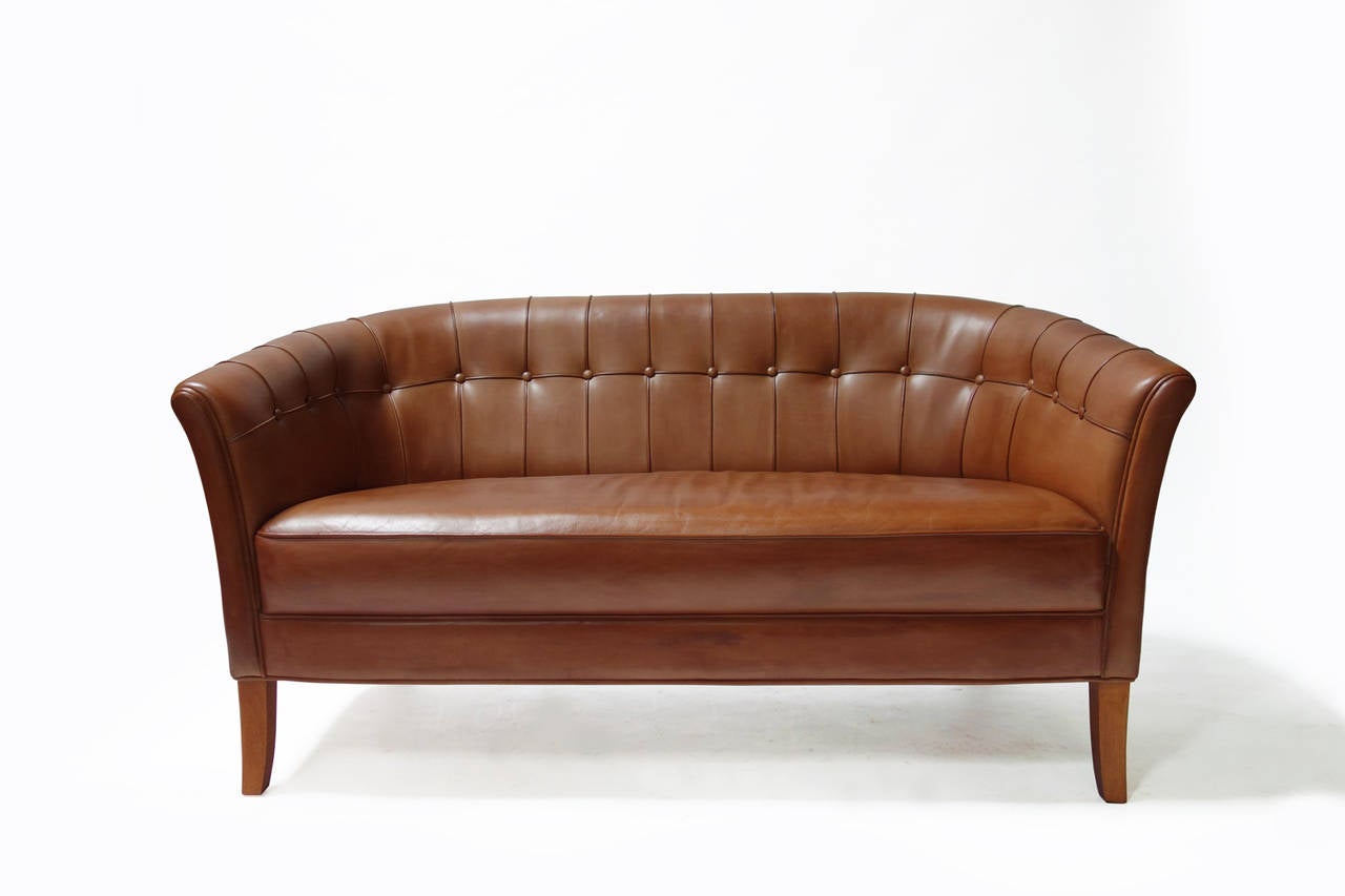 Danish cognac leather sofa with button tufting, harmonious back and seat design. Oak legs