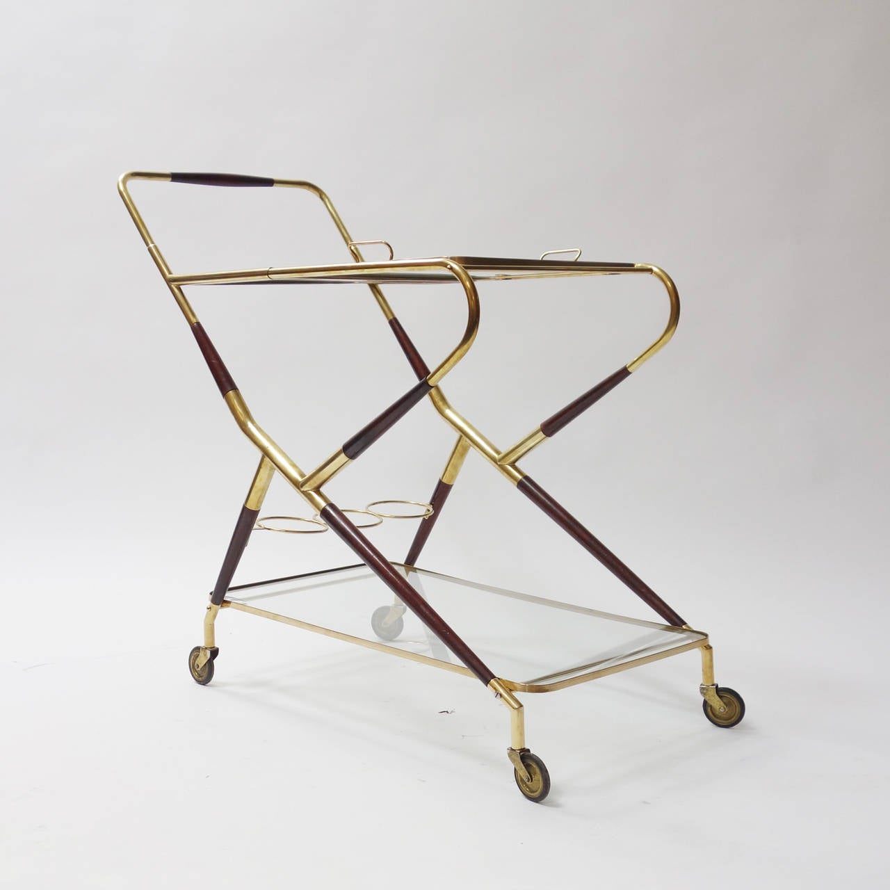 Trolley bar cart in the style of Cesare Lacca, with wood and brass structure.
Two glass shelves and a removable top tray with elegant handles, three bottle holder.