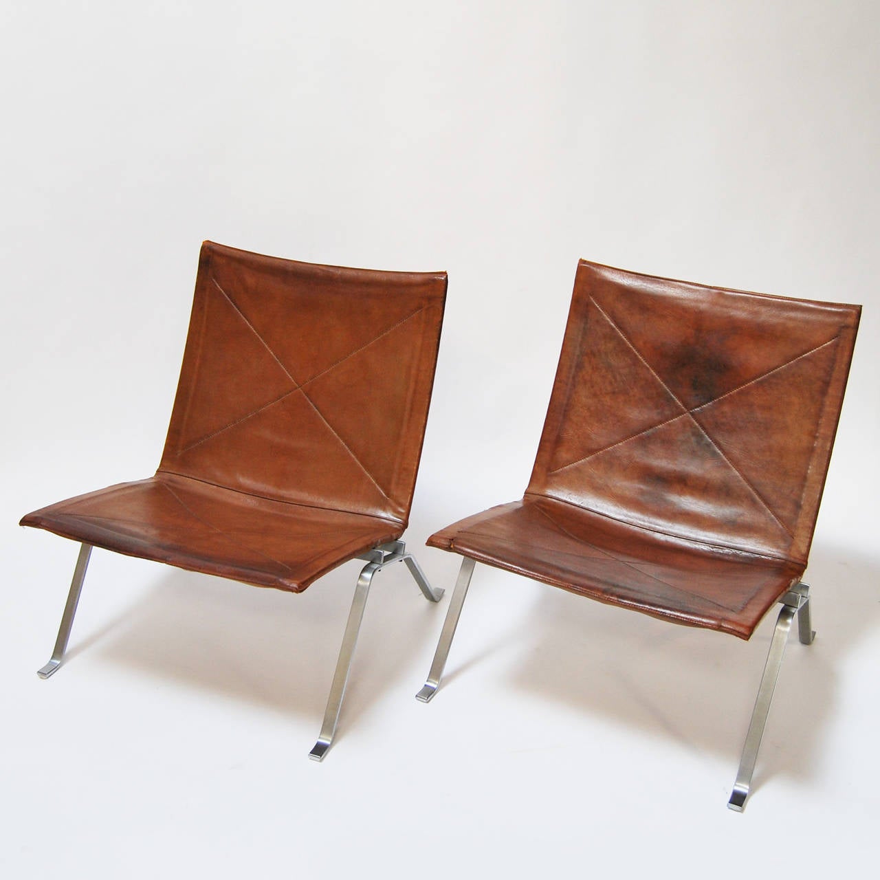 Pair of lounge chairs designed by Poul Kjaerholm in 1956.
Manufactured by E. Kold Christensen. 
Cognac leather seats and matte chrome-plated structured.

Stamp of the manufacture impressed in the structure.