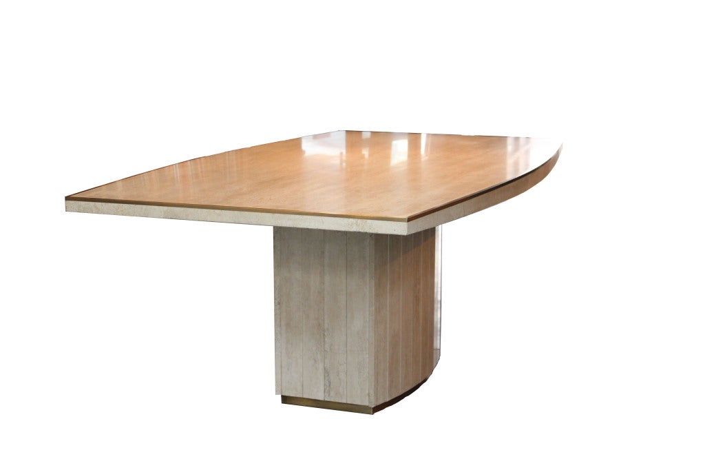 Travertine dining table with brass detail circling the table top and the lower part of the central base.