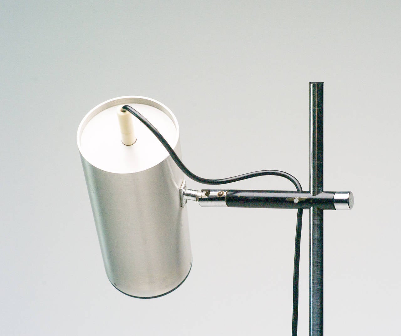 Designed in 1968 and manufactured by Uginox for Ugine-Gueugnon, this stainless steel floor lamp is constructed from a circular, black enameled metal base and stainless steel stem. An elegant and refined fixture, this item features a sliding branch