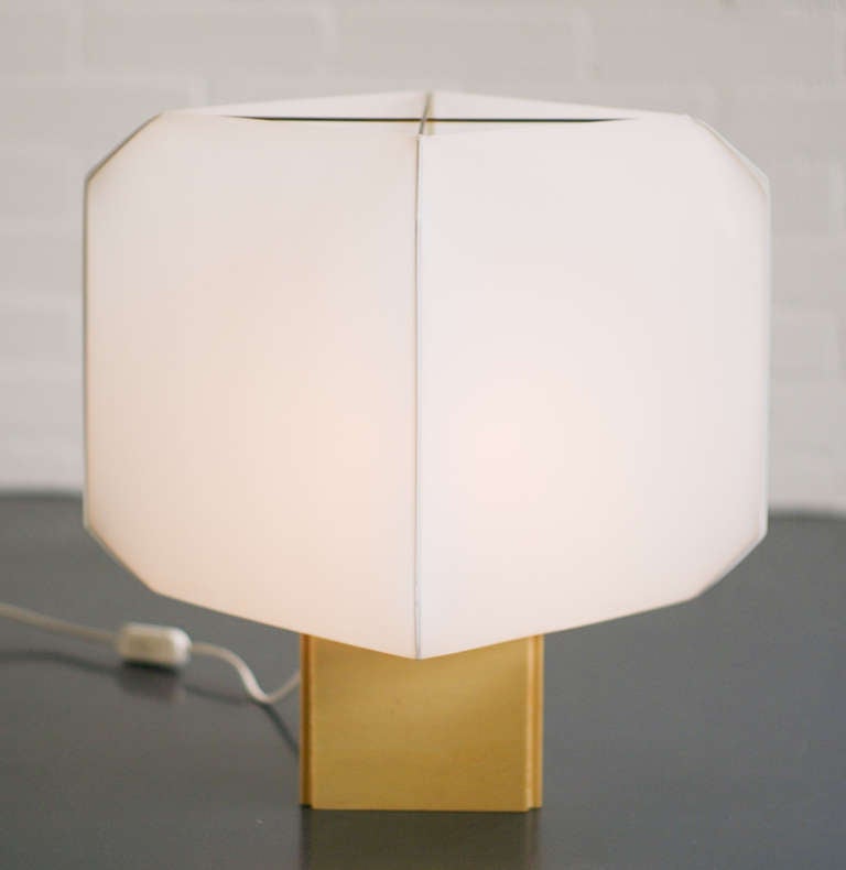 Table lamp on a natural wood base with white plastic shade held in place by two brass rods. 
We offer affordable worldwide shipping. Feel free to inquire!