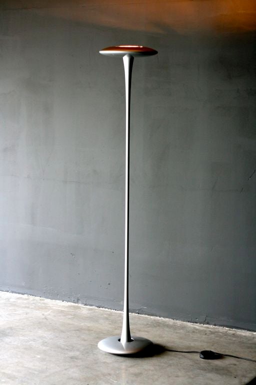 Marc Newson Helice floorlamp designed in 1992 for Flos.
This lamp is composed of aluminium, in 3 parts, connected by a cable inside the body. A color glass diffuser on top diffuses the downward light on the body.
Silver lacquered body and blue