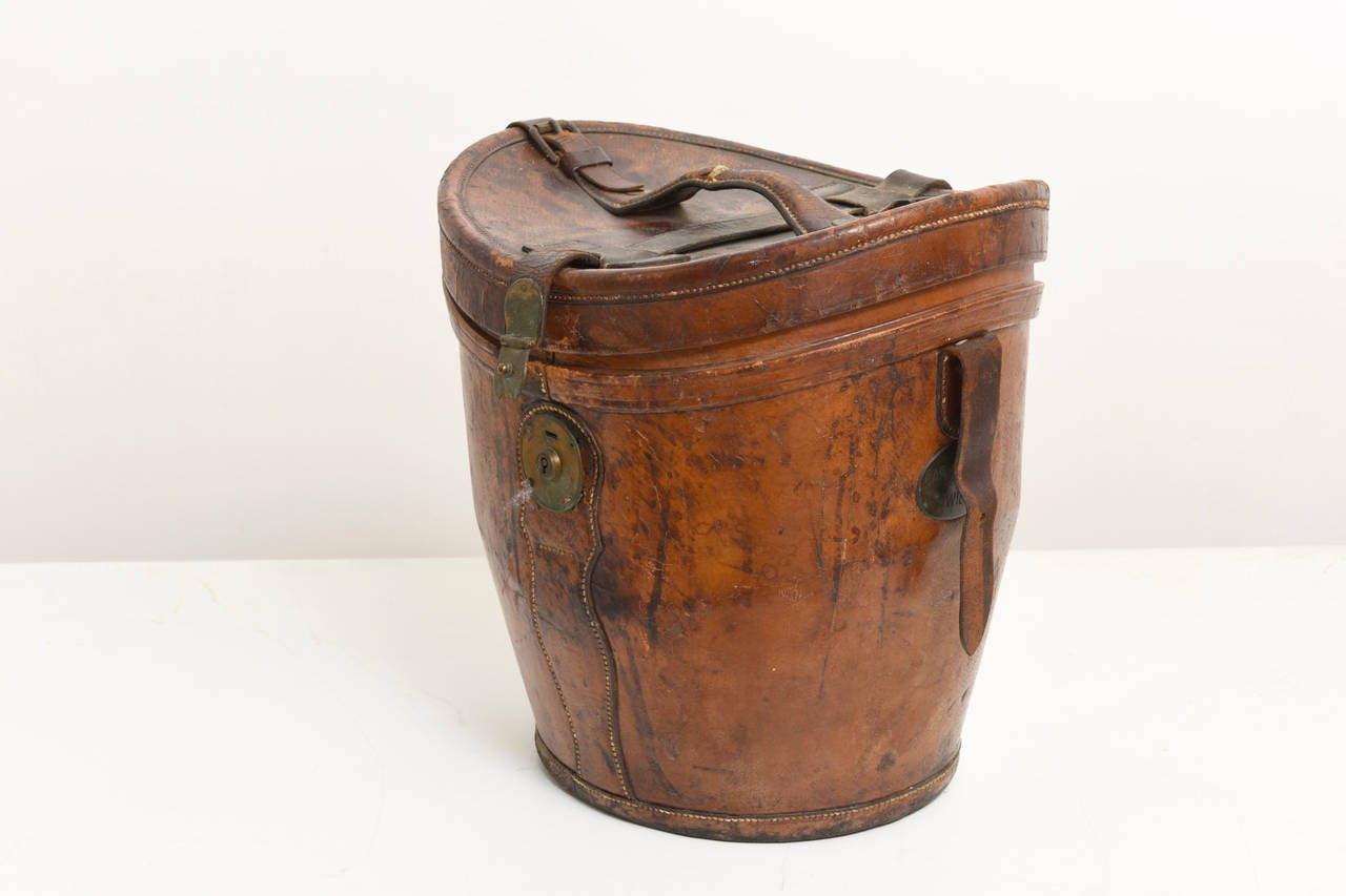It's a wonderful Carl Brunner Wien hat-box with a hanged lid that fastens the box,with a lockable clasp and a strap and buckle which acts as a handle. 

The hat-box is intended to secure the safekeeping of finest hats,in the days when people