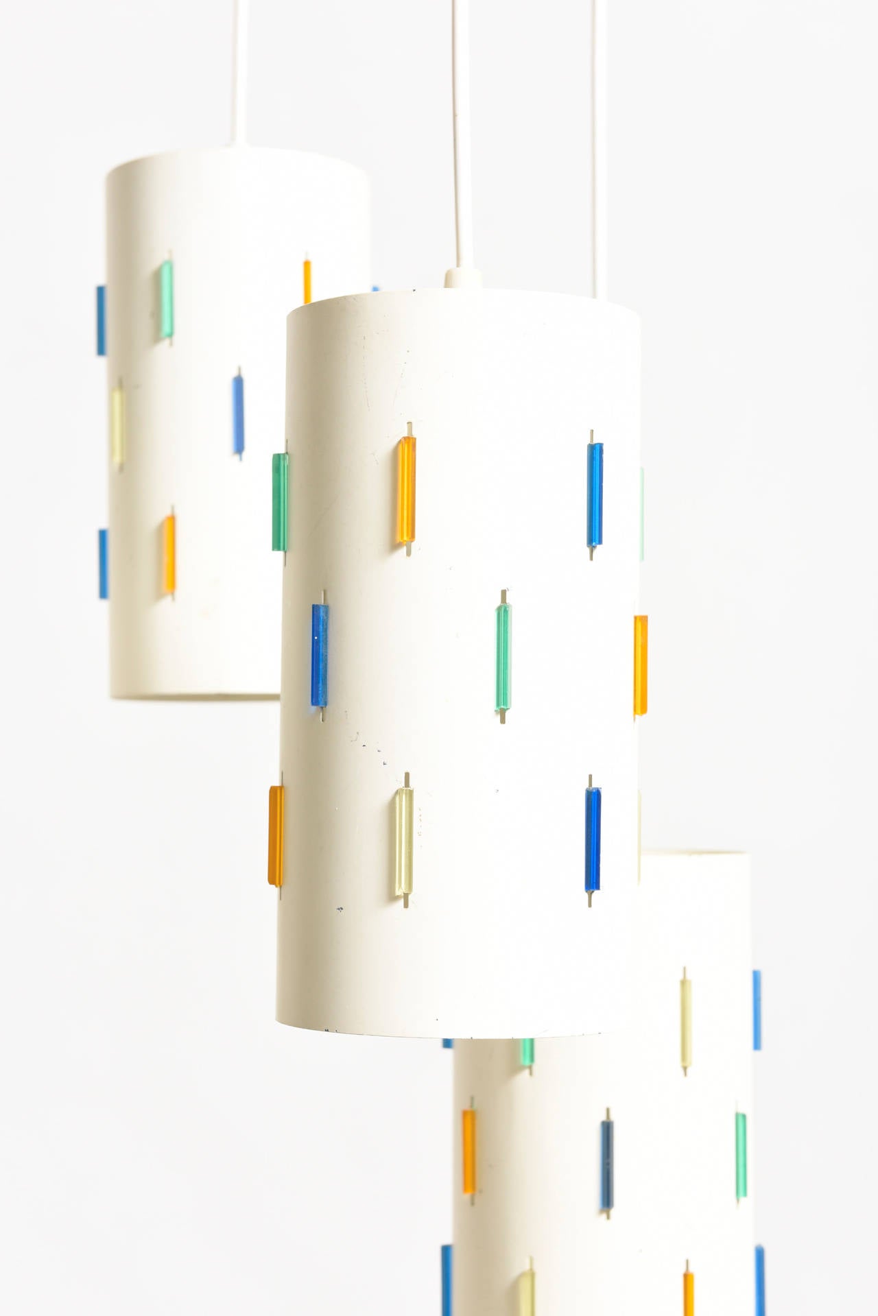 Set of five cylindric pendant lamp with thick colored Lucite inlays. Original condition, white enameled cylinder perforated metal shades with colored Lucite accent reflective insert for better light. Rewired.