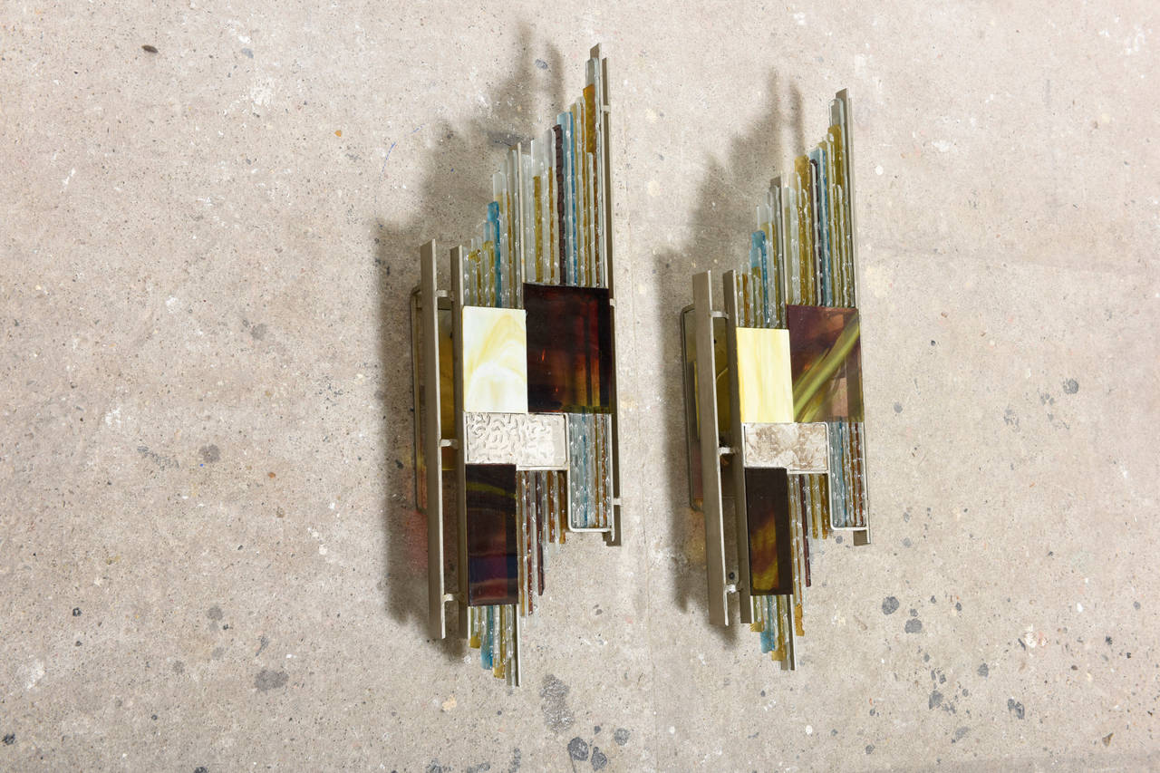 Brutalist glass sconces made of a metal structure with pieces of hand chipped glass, abstract modernist pattern realized in different colors.