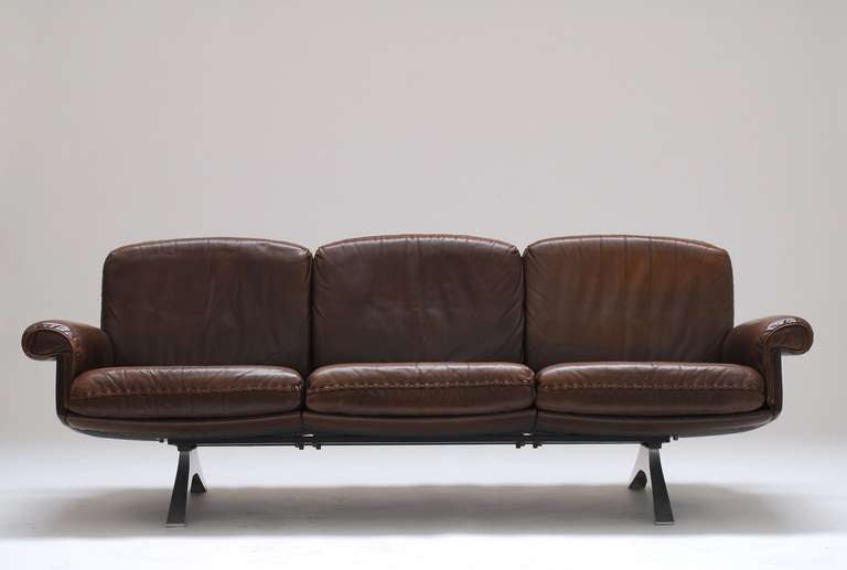 Sofa and club chair in chocolate brown leather. De Sede always uses the best leather around.
It has great patina and no strange marks or scratches. 
The solid inbox base makes it a powerful, yet elegant piece of design. An active, slightly 'hard'