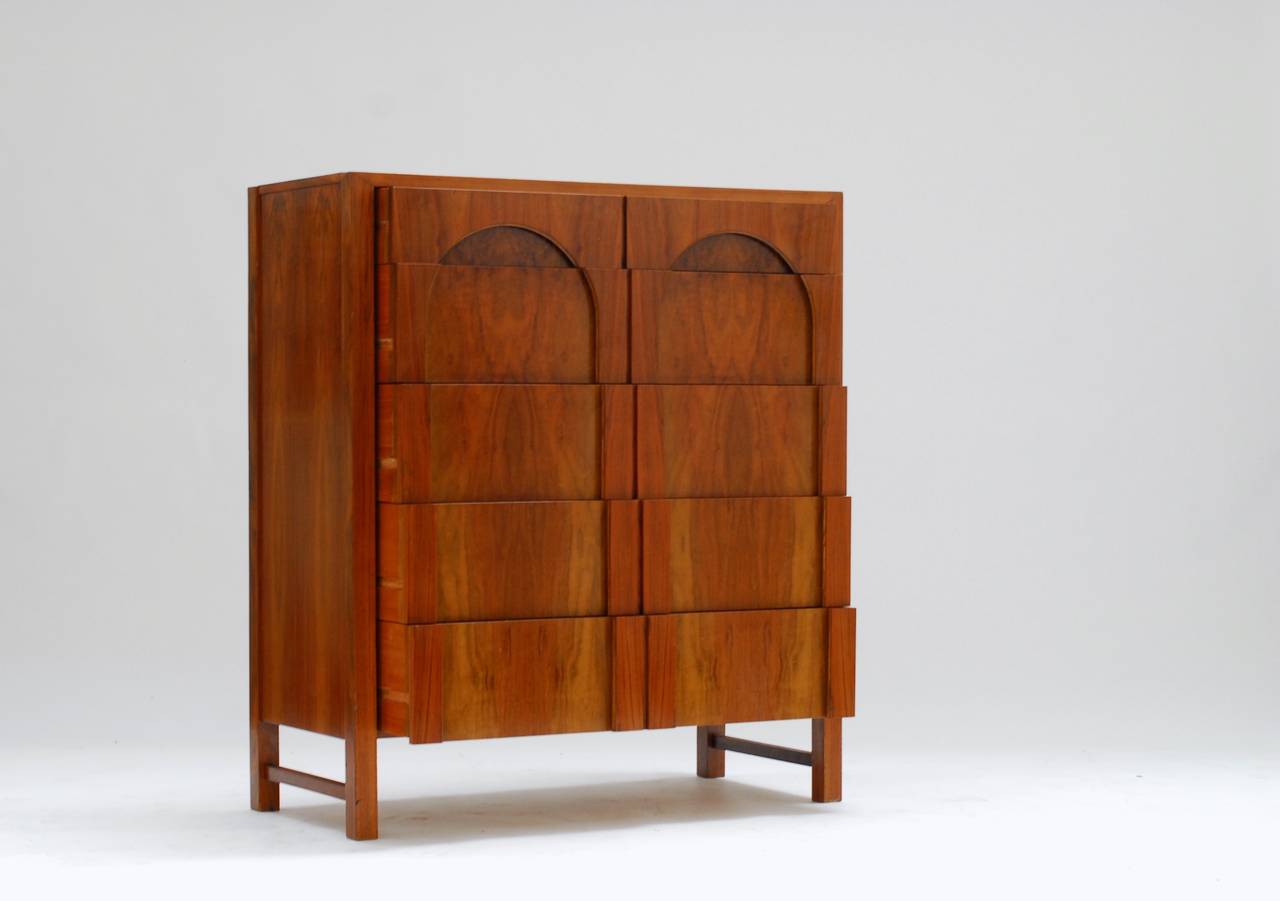 This chest of drawers was made and introduced at an interiors and decorative fair / exhibition in 1960. 
The two Roman bows in this design are remarkable because of it's postmodern character and approach. But we're talking 1960 here. The marriage