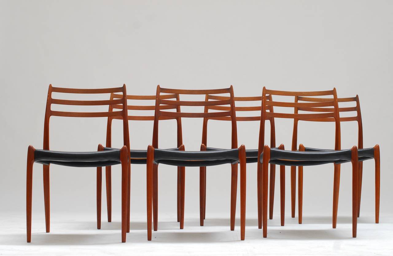 Elegant set of 8 dining chairs model #78 by Niels Otto Møller with very sculptural teakwood frames and original black vinyl seats in good condition. 
Handmade by J.L Møllers Møbelfabrik, circa 1962. Each example is signed with the manufacturer's