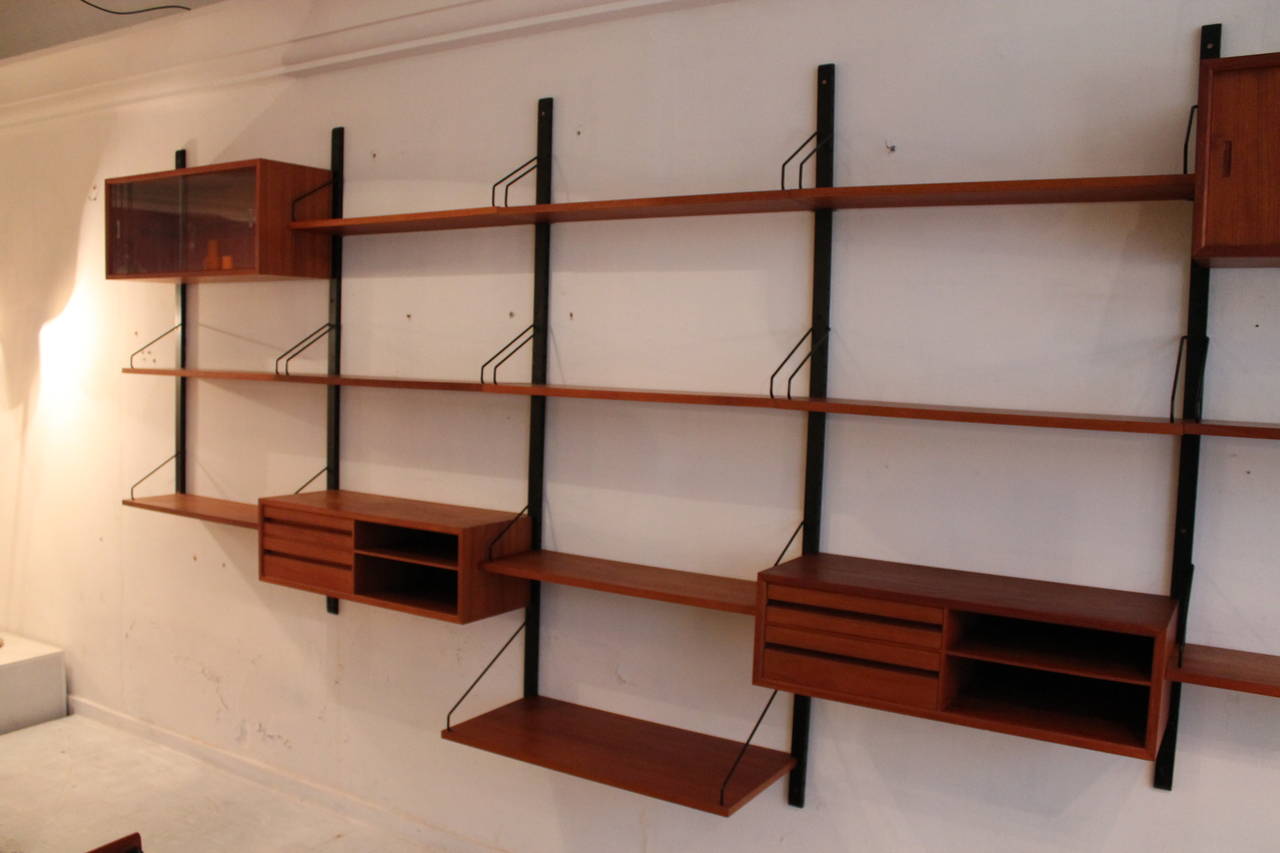 Teak Danish modern wall unit by Poul Cadovius, Denmark, 1950s.

Two cabinets with drawers, one with glass doors and one with teak doors.
12 shelves and five wall holders.

Teakwood, all in good condition.

We ship world wide, contact us for